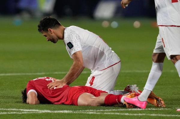 Syria's Mouaiad Alajaan lies on the ground as Iran's Shojae Khalilzadeh comforts him