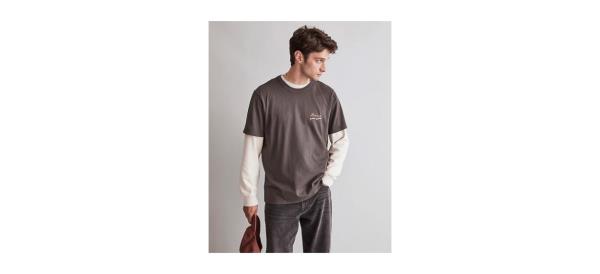a man wearing a brown t-shirt over a long-sleeved shirt