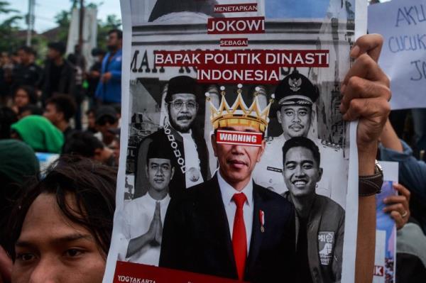 A protester holding up a placard showing photos of Jokowi and his family members and co<em></em>ndemning for creating a dynasty