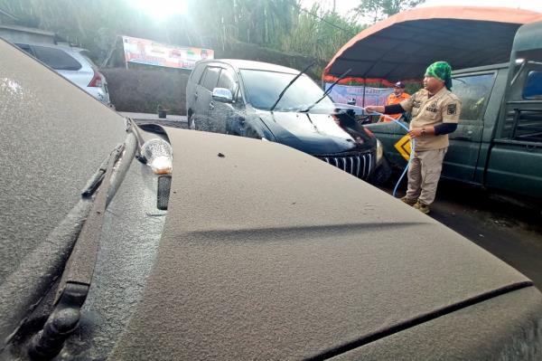 A disaster management agency official washes a car covered in volcanic ash from the eruption of Mount Marapi in Agam, West Sumatra, Indonesia, Sunday, Jan. 14, 2024.