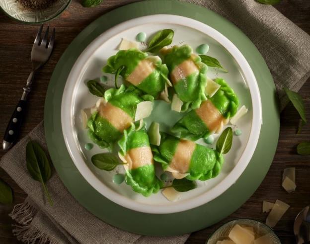 A close-up shot of a plate of green and yellow striped stuffed dumplings, also known as pierogies.