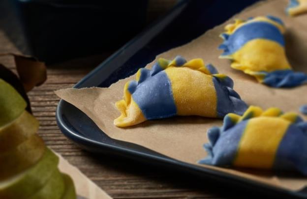 A close-up shot of blue and yellow stuffed dumplings, also known as pierogies. 