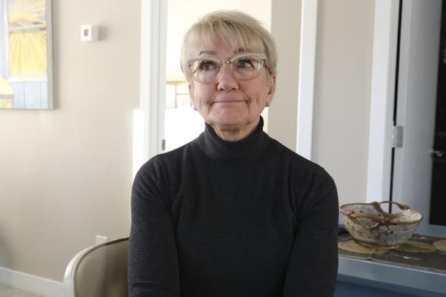 Gayle Nemeth sits in a chair in her modern looking co<em></em>ndo kitchen
